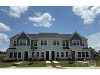 New two-story townhomes feature modern exteriors with gray siding and landscaped front yards beneath a partly cloudy sky at 5115 Orchardview Way # 24, Charlotte, NC 28216