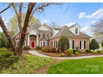 Stately brick home with a red door, black shutters, and manicured landscaping at 10809 Wicklow Brook Ct, Charlotte, NC 28277