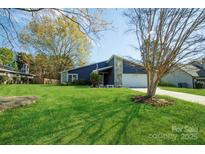 Inviting two-story home boasting a lush green lawn and a charming combination of stone and blue siding at 11014 Fox Mill Ln, Charlotte, NC 28277