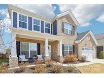 Charming two-story brick home with a welcoming front porch and well-manicured landscaping and partial blue sky at 13102 Petrel Pl, Charlotte, NC 28278