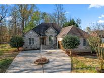 Charming brick home featuring a circular driveway, well-manicured lawn, and mature trees at 103 Devonshire Ln, Salisbury, NC 28146