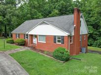 Charming brick home featuring a well-maintained lawn, mature trees, and black window shutters at 167 Cedar Ln, Troutman, NC 28166