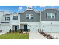 Charming townhome with well-manicured lawn, attached garage, and inviting blue front door at 1743 Braemar Village Dr, Monroe, NC 28110