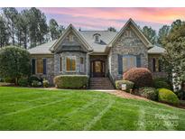 Charming stone home featuring a well-manicured lawn and lush landscaping, creating inviting curb appeal at 1849 Oakmont Dr, Denver, NC 28037
