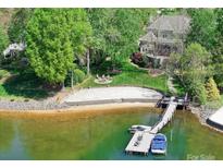 Stunning lakefront property featuring a private beach, dock, and lush green landscaping at 19040 Mary Ardrey Cir, Cornelius, NC 28031