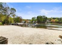 Serene waterfront with a private beach, dock, and boat slips amidst lush greenery at 19040 Mary Ardrey Cir, Cornelius, NC 28031