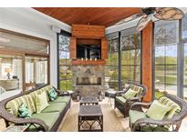Inviting sunroom with a stone fireplace, a TV, wicker furniture, and serene water views at 19040 Mary Ardrey Cir, Cornelius, NC 28031