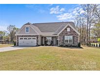 Charming one-story home featuring a stone and siding facade, a two-car garage, and a well-maintained lawn at 2017 Autumn Dr, Monroe, NC 28110