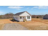 Charming white cottage-style home with a covered front porch and a well-maintained yard in a rural setting at 603 Mt. Wesley Church Rd, Hiddenite, NC 28636