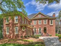 A beautiful red brick home with manicured landscaping, blue sky, and mature tree in this exterior elevation at 8912 Heydon Hall Cir, Charlotte, NC 28210