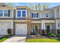 Charming townhome featuring stone accents, a one-car garage, and a beautifully landscaped front yard at 1066 Chicory Trce, Lake Wylie, SC 29710