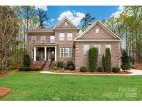 Charming two-story brick home featuring a well-manicured lawn, tasteful landscaping, and a welcoming covered porch at 10823 Preservation Park Dr, Charlotte, NC 28214