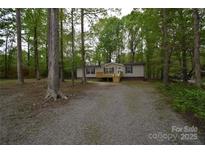 Charming single-story home featuring a front porch, set among beautiful trees, and a spacious gravel driveway at 121 Silver Fox Ct, Mount Holly, NC 28120