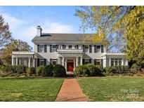 Stately two-story home with a red brick walkway, lush lawn, manicured bushes, and a red front door at 1212 Queens Rd, Charlotte, NC 28207