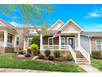Inviting two-story home showcasing a delightful front porch, picturesque landscaping, and an American flag at 12424 Bradford Park Dr, Davidson, NC 28036