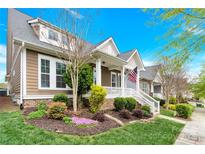 Charming two-story home with landscaped yard, welcoming front porch and an American flag at 12424 Bradford Park Dr, Davidson, NC 28036