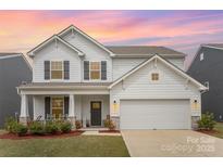 Charming two-story home with gray shutters, a covered porch, an attached garage and colorful twilight sky at 2893 Yeager Nw Dr, Concord, NC 28027