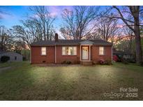 Charming brick home featuring a well-manicured lawn and mature trees against a twilight sky at 304 Simrill Ave, York, SC 29745