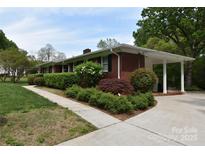 Charming red brick home featuring a covered carport and beautifully landscaped front yard at 8608 Cedarbrook Dr, Charlotte, NC 28215