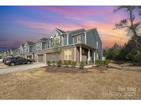 Charming townhome with a brick facade, two-car garage, manicured lawn, and a welcoming covered porch at 9031 Odell Corners Nw Blvd, Concord, NC 28027