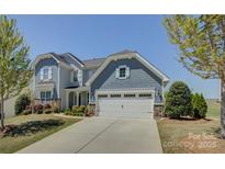 Beautiful two-story home with blue siding, white trim, a two-car garage, and a well-manicured front lawn at 16524 Palisades Commons Dr, Charlotte, NC 28278