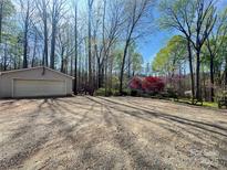 Detached garage with gravel driveway and ample parking space surrounded by a beautiful tree-filled lot at 245 Clontz Hill Rd, Troutman, NC 28166
