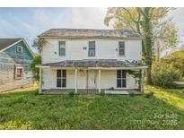 Two-story white home with a covered porch and overgrown landscaping at 303 E Fisher St, Salisbury, NC 28144