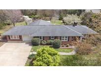 A charming brick home featuring a well-maintained roof and an attached garage, all set within a beautifully landscaped yard at 317 S Lineberry St, Troy, NC 27371