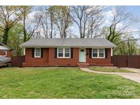 Charming brick home with a well-maintained lawn, complemented by black shutters and a cheerful, light-blue front door at 3826 Crestridge Dr, Charlotte, NC 28217