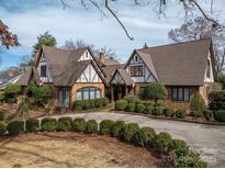 Charming Tudor-style home featuring brick accents, gabled roofs, and meticulously manicured landscaping at 418 3Rd Ne St, Hickory, NC 28601