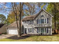 Charming two-story home with gray siding, dark shutters, attached two-car garage and beautifully landscaped yard at 2439 Heathershire Ln, Matthews, NC 28105