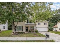 Two-story home with mature trees, covered porch, and a driveway leading to a two-car garage at 3009 Early Rise Ave, Indian Trail, NC 28079