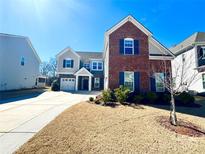 Two-story home with brick and siding exterior, a two-car garage, and a well-maintained lawn and garden at 9677 Garamont Nw Pkwy, Concord, NC 28027