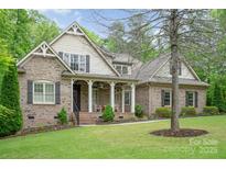 Charming brick home featuring a covered porch, manicured lawn, and mature trees enhancing curb appeal at 112 Spring Branch Rd, Fort Mill, SC 29715