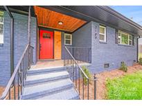 Charming home featuring a striking red door, beautiful wood ceiling, and a classic blue brick facade at 2109 Tarlton Dr, Matthews, NC 28105