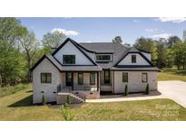 Charming two-story home with light brick, black trim, a covered porch, and a manicured lawn at 3500 Manna Ln, Mount Holly, NC 28120