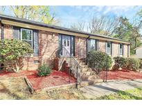 Charming brick home featuring a beautiful front entrance with a decorative purple door and landscaped yard at 7034 Leaves Ln, Charlotte, NC 28213