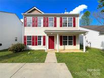 Inviting two-story home featuring a well-manicured lawn, red shutters, and a charming front porch at 7147 Henderson Valley Ln, Charlotte, NC 28269