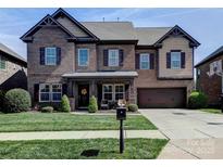 Charming two-story brick home with a well-manicured lawn, attached garage, and inviting front porch at 9622 Harvest Pond Nw Dr, Concord, NC 28027