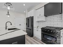 Modern kitchen with white cabinets, black appliances, stylish countertops and wood floors at 143 Mills Garden Rd, Statesville, NC 28625