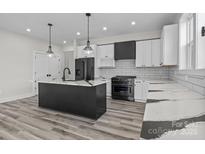 Modern kitchen featuring white cabinets, subway tile backsplash, and a black center island with marble countertops at 143 Mills Garden Rd, Statesville, NC 28625
