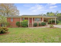 Charming brick home featuring a covered porch, well-kept lawn, and a convenient carport at 303 Windy Rush Rd, Kannapolis, NC 28081