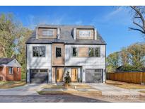Modern duplex featuring light gray siding, two garage doors, wooden accents and a blue sky at 3129 Rush Ave, Charlotte, NC 28208