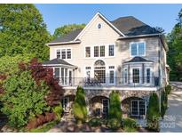 Stunning rear view of the home with a stone facade, large windows, and a spacious balcony overlooking landscaped gardens at 338 Fairfield Ct, Mount Gilead, NC 27306