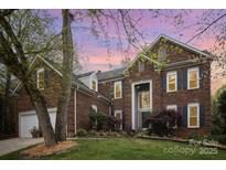 Elegant brick home with dark shutters, lush landscaping, and a well-manicured lawn under a vibrant dusk sky at 3409 Pondview Ln, Charlotte, NC 28210