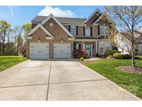 Charming brick two-story home with attached two car garage and a well-manicured lawn at 5854 Crimson Oak Ct, Harrisburg, NC 28075