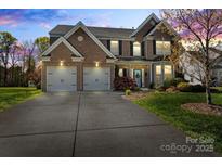 Charming two-story brick home with a manicured lawn and a two-car garage, perfect for Gathering living at 5854 Crimson Oak Ct, Harrisburg, NC 28075