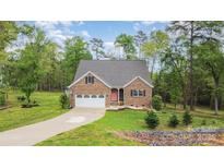 Charming brick home with attached garage, long driveway, and well manicured lawn at 1027 Williamston Dr, Marshville, NC 28103