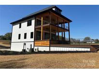 View of a modern three-story home featuring a large deck and multiple balconies, perfect for outdoor living and entertaining at 15170 Cove Point Ln, Norwood, NC 28128