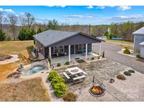 Charming home featuring a welcoming front porch, patio with a fire pit, and meticulously landscaped surroundings at 1595 Cheatham Ford Rd, Hiddenite, NC 28636